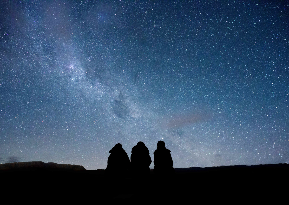 Silhouette of three people from behind looking at the milky way